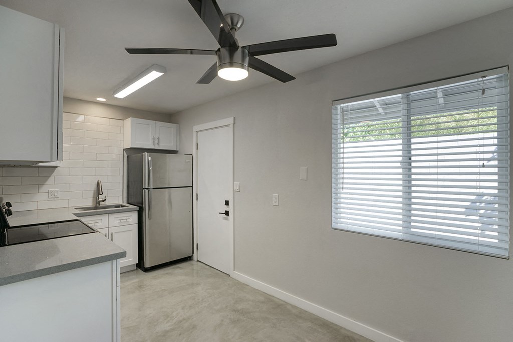 an empty kitchen with a ceiling fan and a window