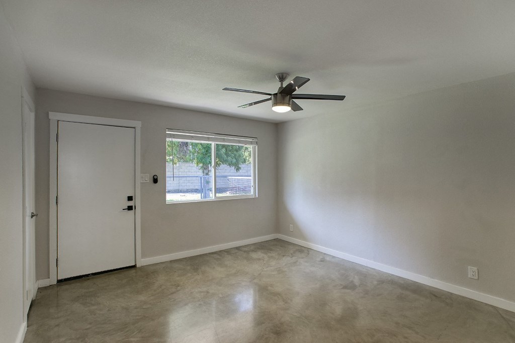 an empty living room with a ceiling fan and a window