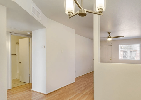 the living room and dining room of an empty house with white walls and wood floors