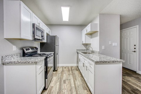 A kitchen with white cabinets and a granite countertop.