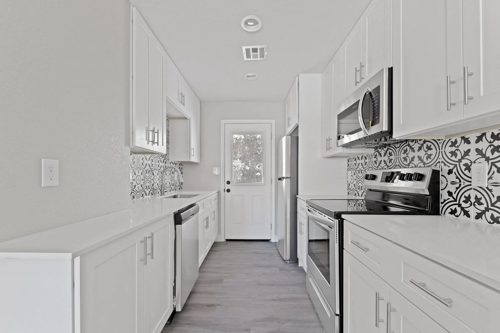 A white kitchen with a tile backsplash and a window.