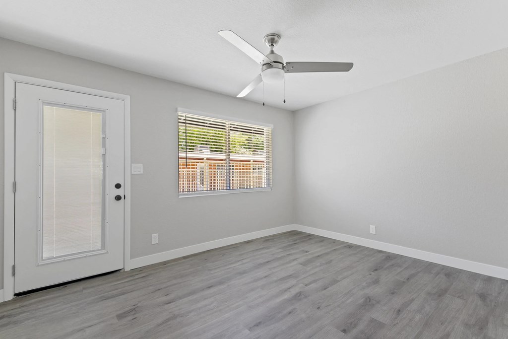 A room with a ceiling fan and a window with blinds.