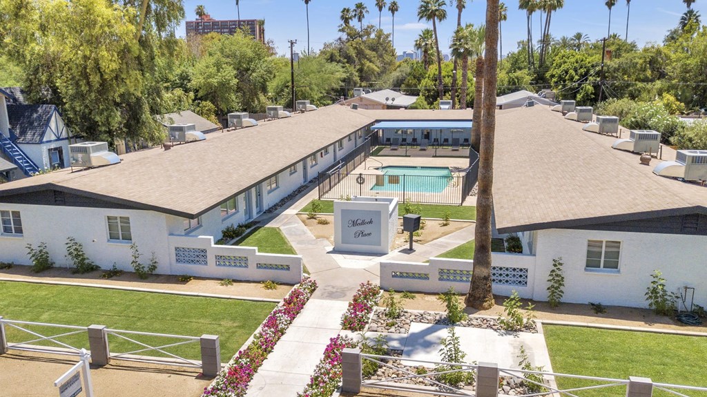 A white building with a pool in front of it.