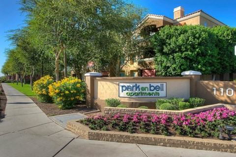 a sign in front of a building with flowers and trees