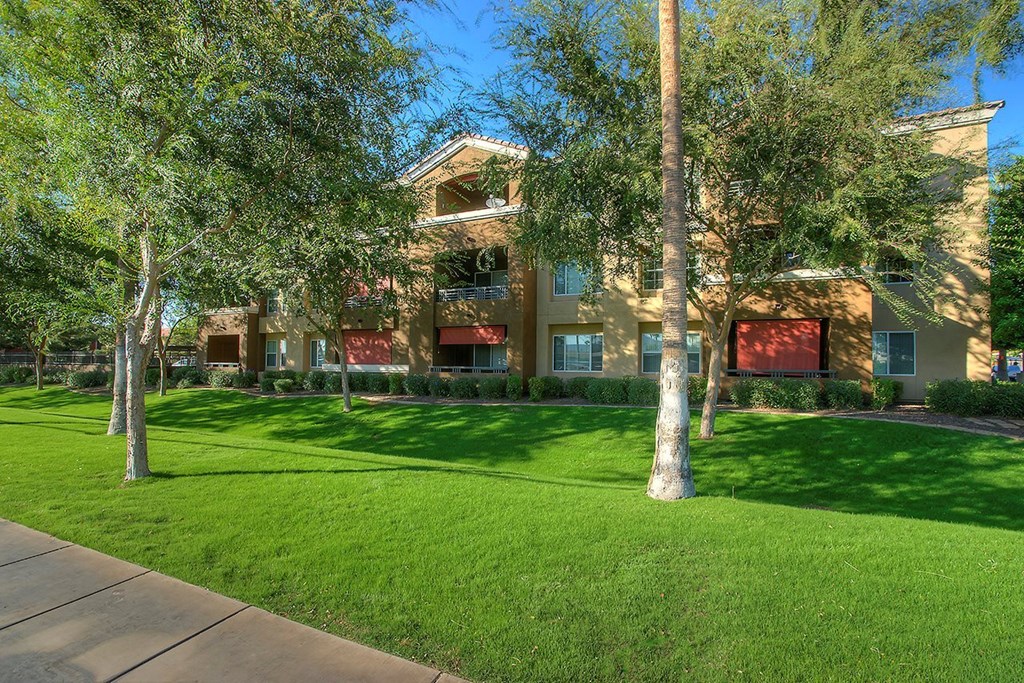 a large building with green grass and trees in front of it