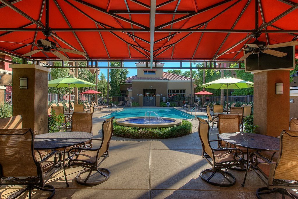a patio with tables and chairs and a swimming pool