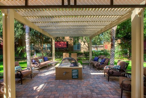 a covered patio with a fire pit and chairs