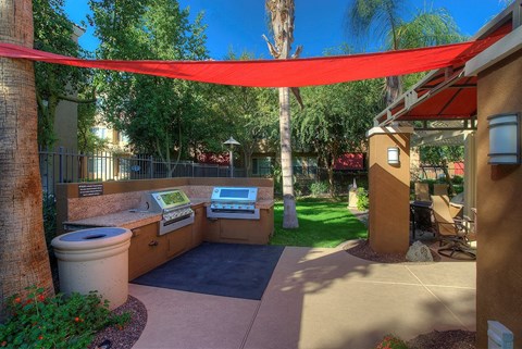 a patio with a barbecue grill and a red canopy