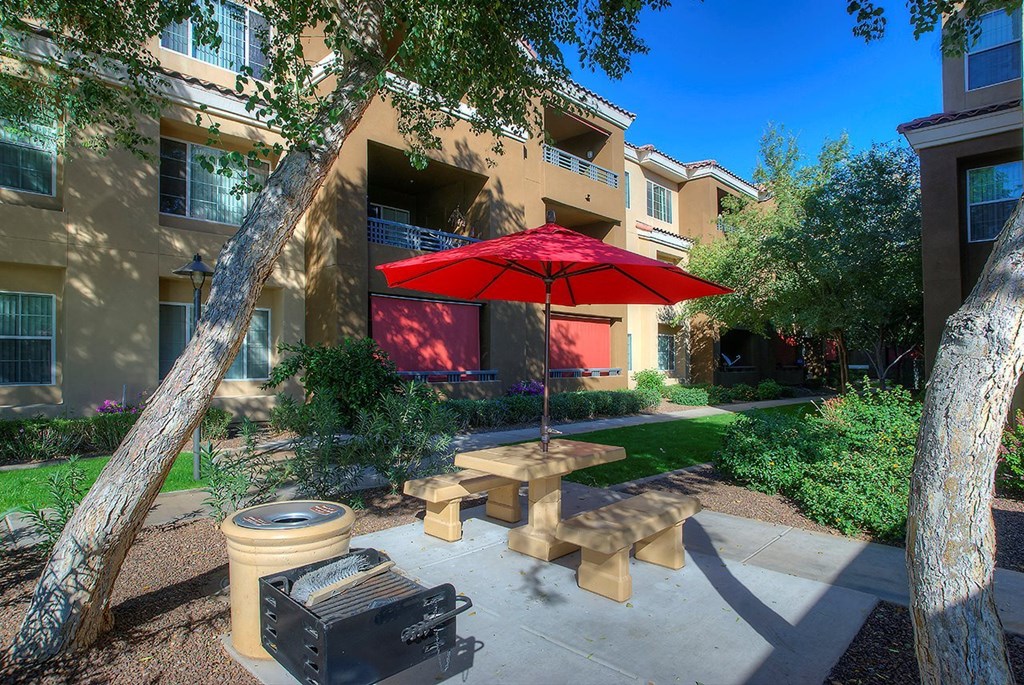a patio with a red umbrella in front of an apartment building