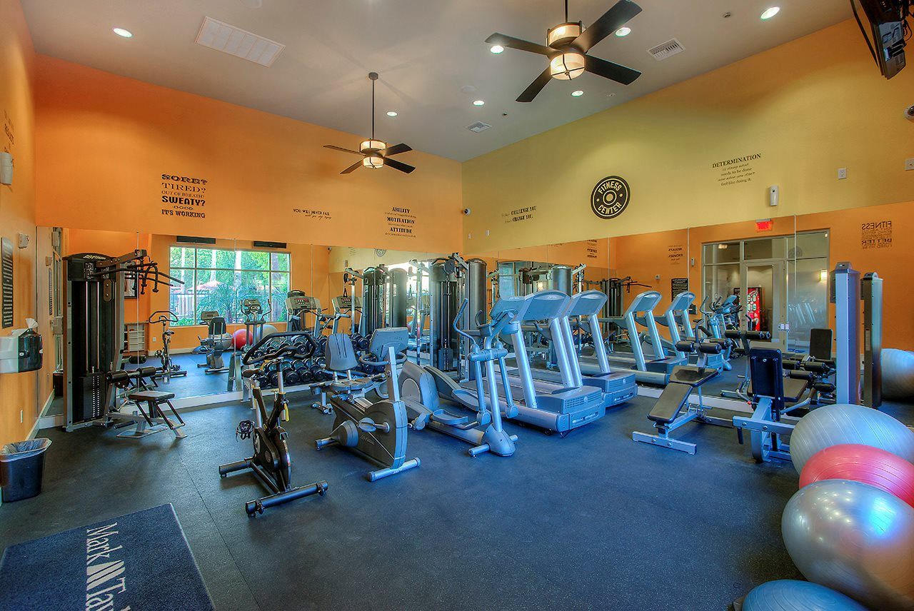 a gym with cardio equipment and weights on the floor