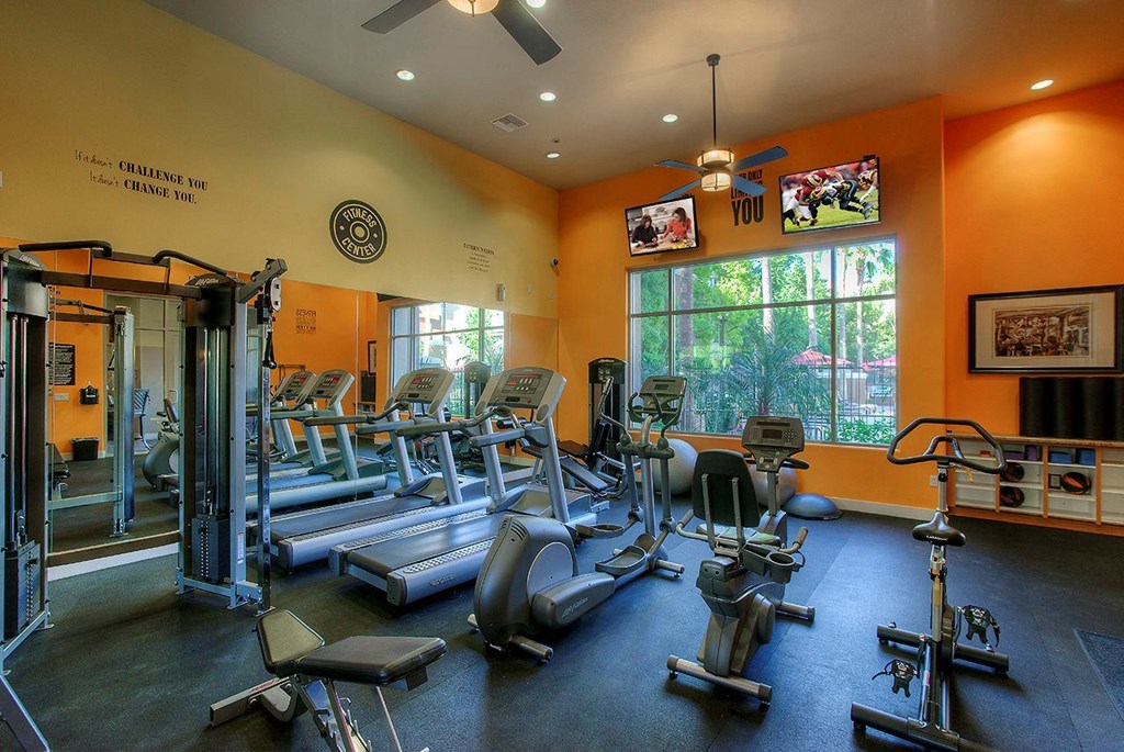 a gym with cardio equipment and a window