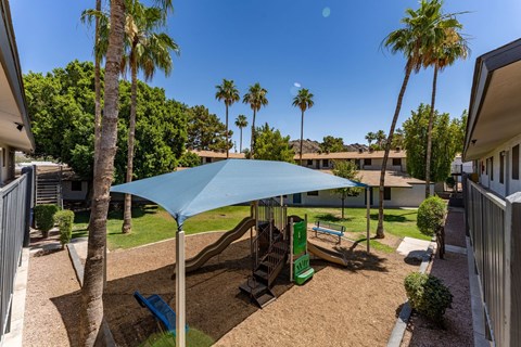 A blue umbrella shades a playground.