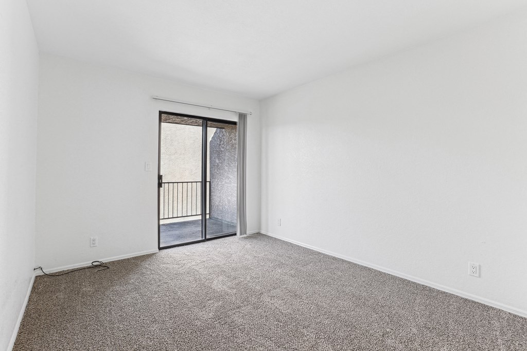 A room with a carpeted floor and a sliding glass door.