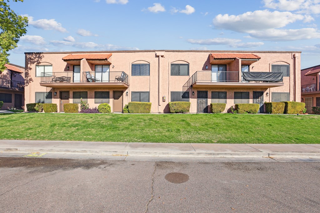 A row of apartment buildings with balconies and green lawns.