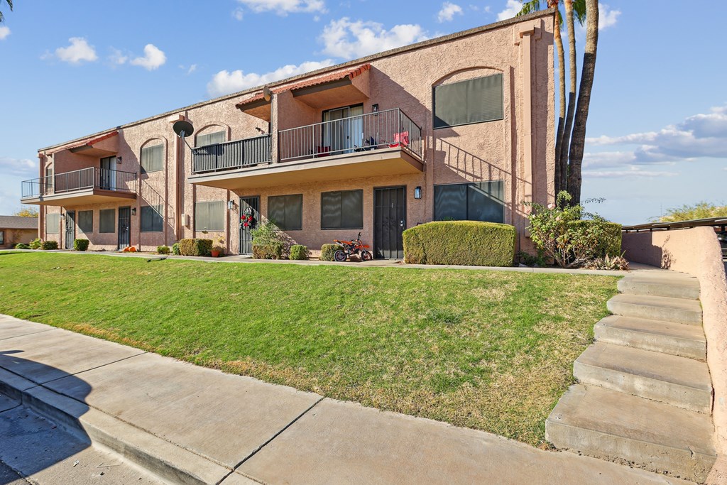 A building with a balcony and a green lawn in front.