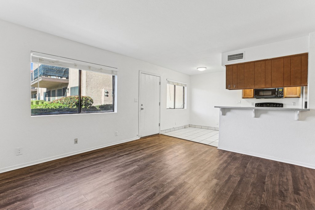 A room with wooden floors and a window showing an outdoor balcony.
