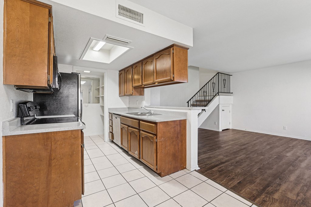 A kitchen with wooden cabinets and a black refrigerator.