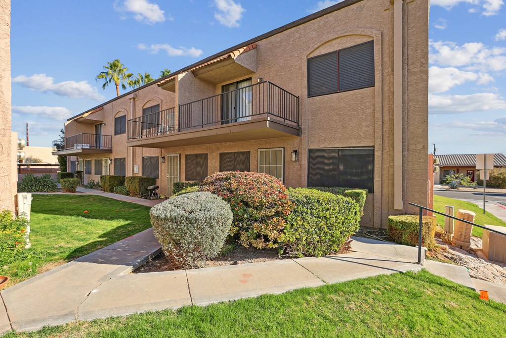 A building with a balcony and a green bush in front.