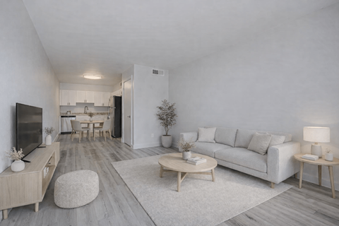 A modern living room with a white couch, wooden coffee table, and a television.