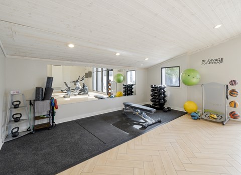 A gym with a variety of equipment including a bench press, kettlebells, and a squat rack.