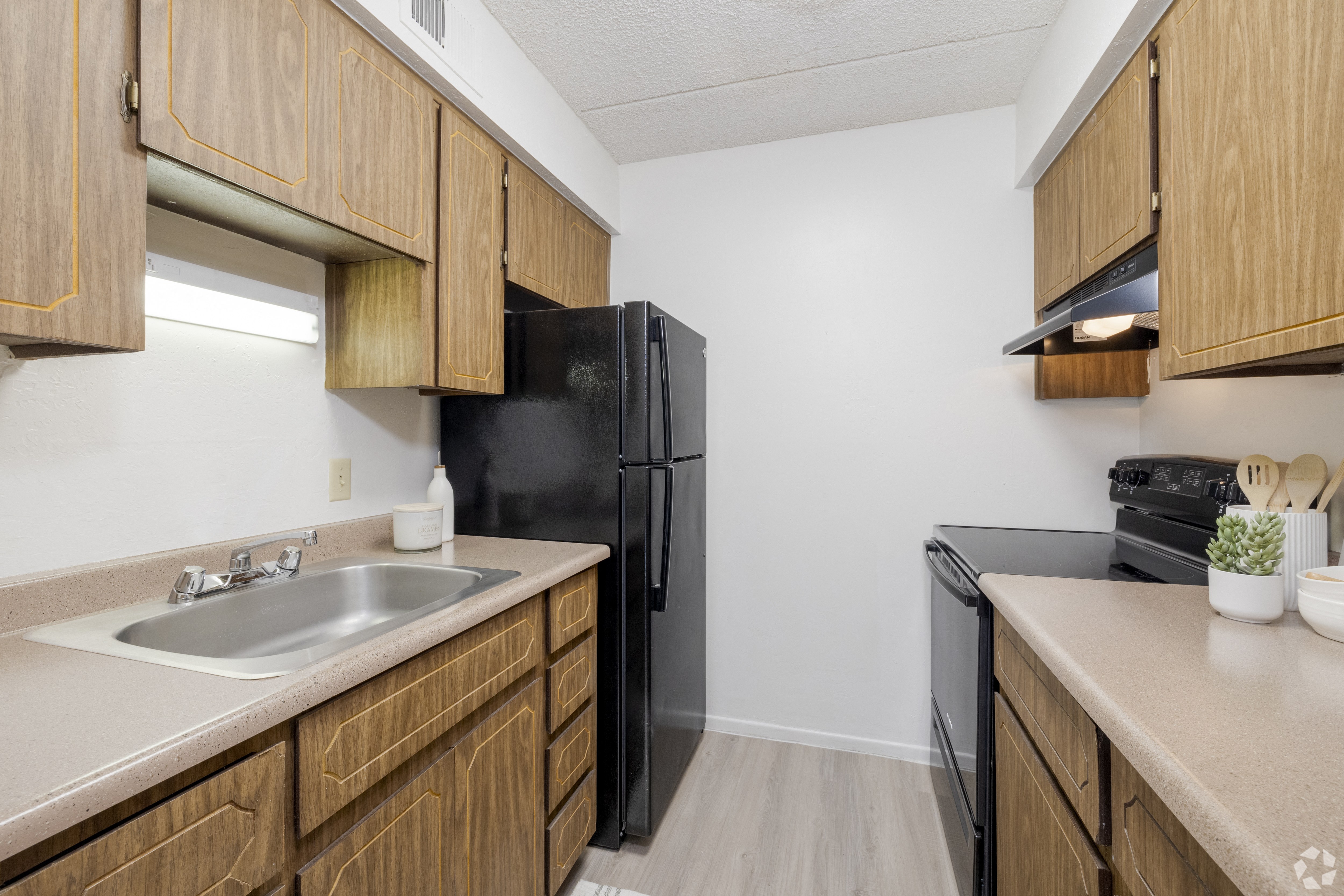 A kitchen with a black refrigerator and wooden cabinets.