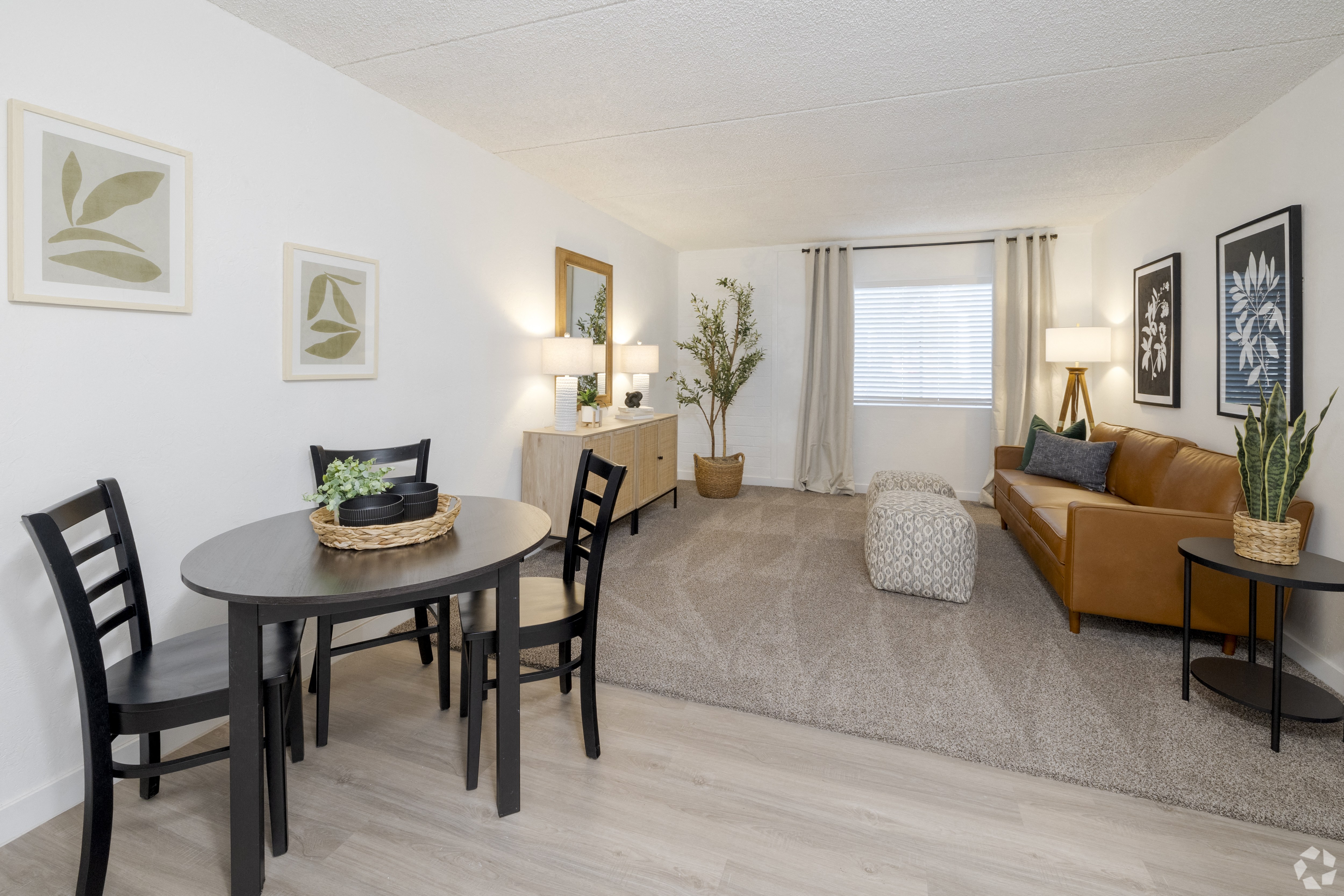 A living room with a brown couch, a round table with chairs, and a rug.