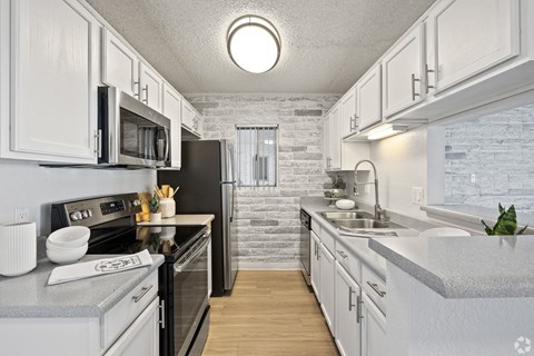 A kitchen with white cabinets and a black refrigerator.