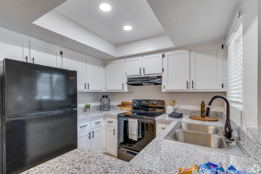 an updated kitchen with granite counter tops and white cabinets