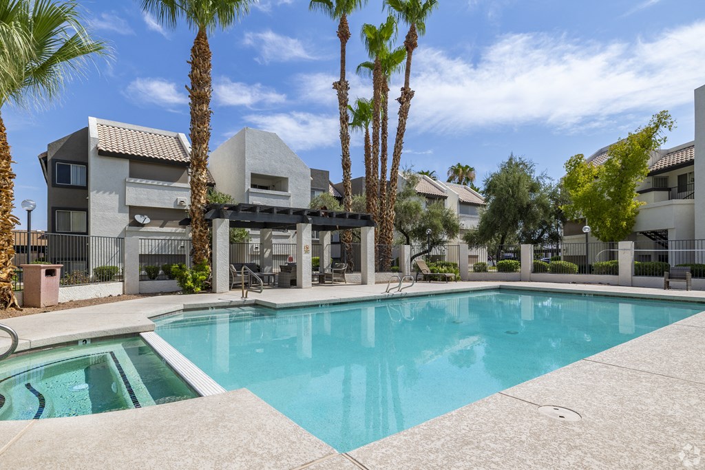 a swimming pool with palm trees in front of an apartment building