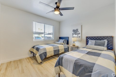 two beds in a bedroom with a ceiling fan and a window