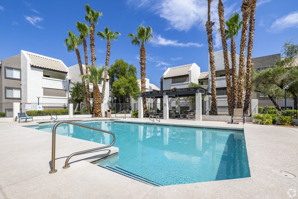 a swimming pool with palm trees and buildings in the background