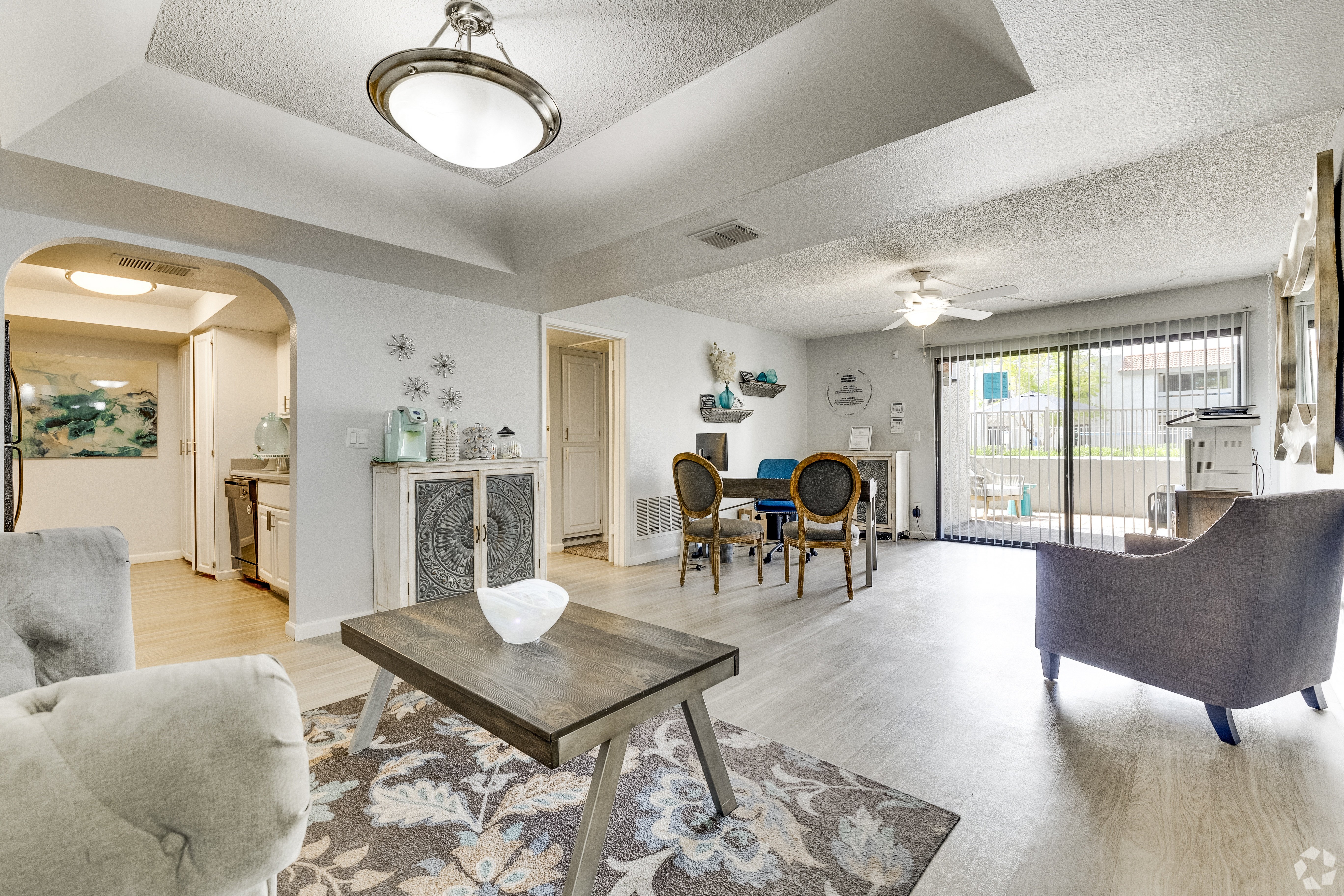 A living room with a grey couch, a coffee table, and a dining table with chairs.