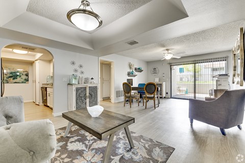 A living room with a grey couch, a coffee table, and a dining table with chairs.