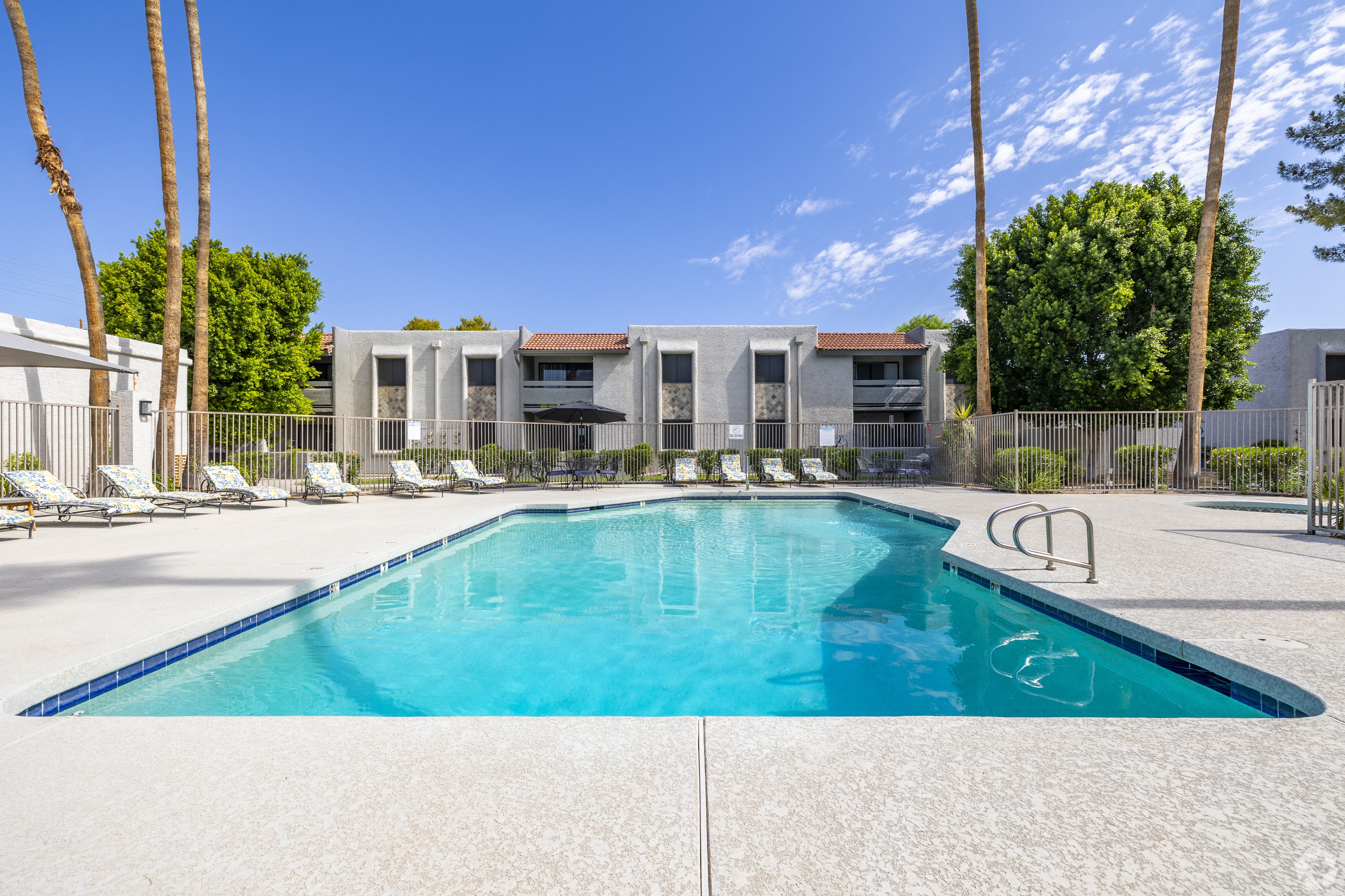 A swimming pool in front of a building with palm trees.
