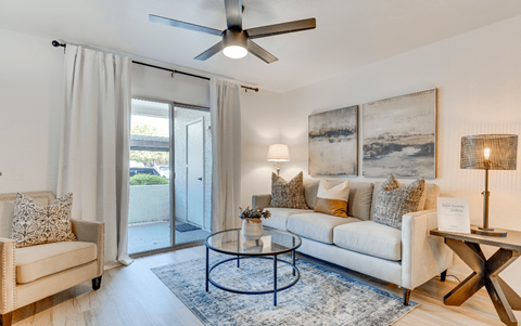 A living room with a white couch, a coffee table, and a ceiling fan.