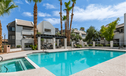 a swimming pool with palm trees in front of an apartment building