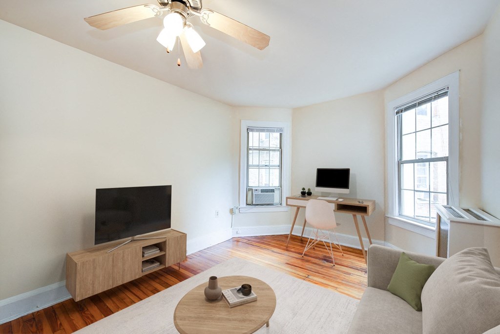 A living room with a television, a desk, and a couch.
