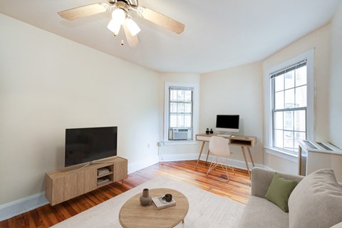 A living room with a television, a desk, and a couch.