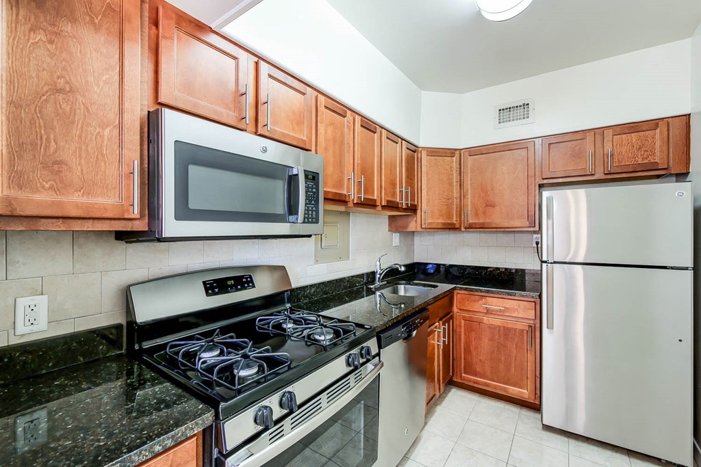 renovated kitchen with stainless steel appliances and oak cabinetry at clarence house apartments in van ness washington dc