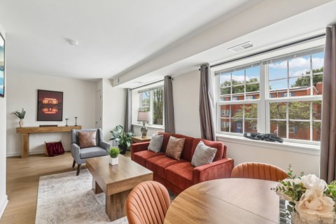 A living room with a red couch and a wooden table.