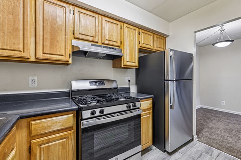 A kitchen with wooden cabinets and a black refrigerator.