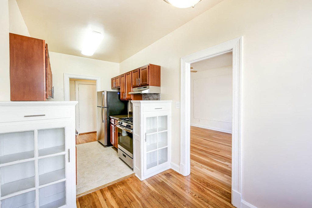 vacant dining area with view of kitchen and living area with hardwood floors at the frontenac apartments in van ness washington dc