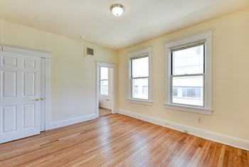 vacant bedroom with hardwood floors, and large windows at twin oaks apartments columbia heights washington dc - Photo Gallery 15
