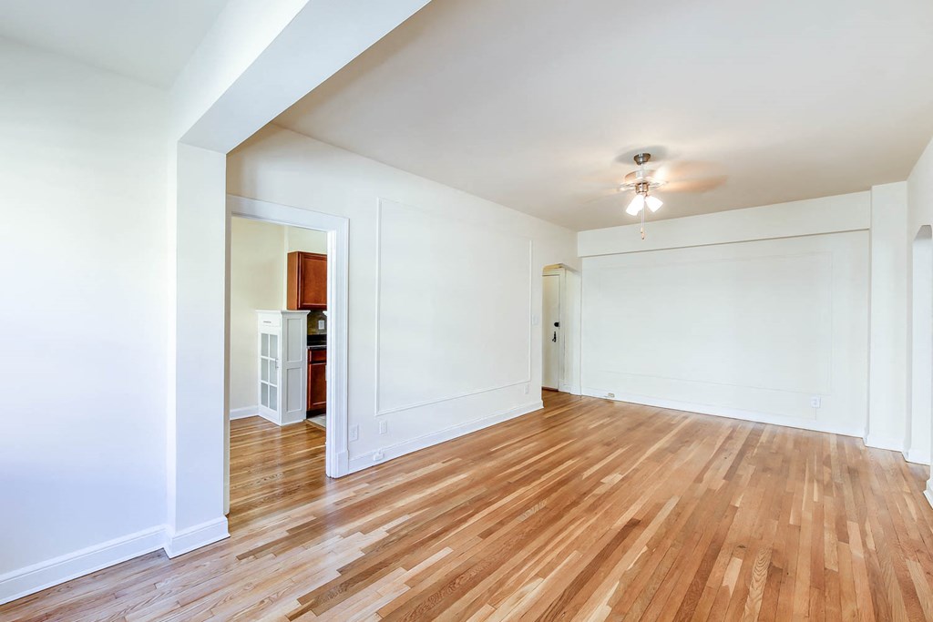vacant living area with hardwood floors, ceiling fan and view of kitchen at the frontenac apartments in van ness washington dc