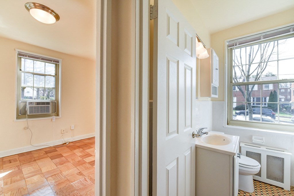 hallway view of living area and bathroom with large windows and hardwood flooring  at 1401 sheridan apartments in washington dc