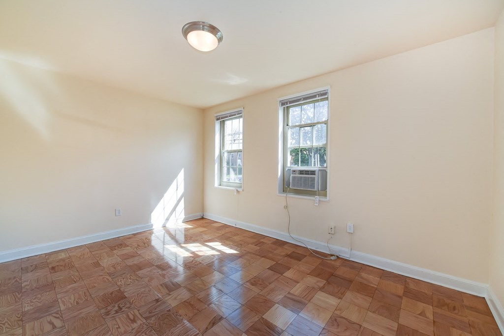 vacant living area with hardwood flooring and large windows at 1401 Sheridan apartments in washington dc