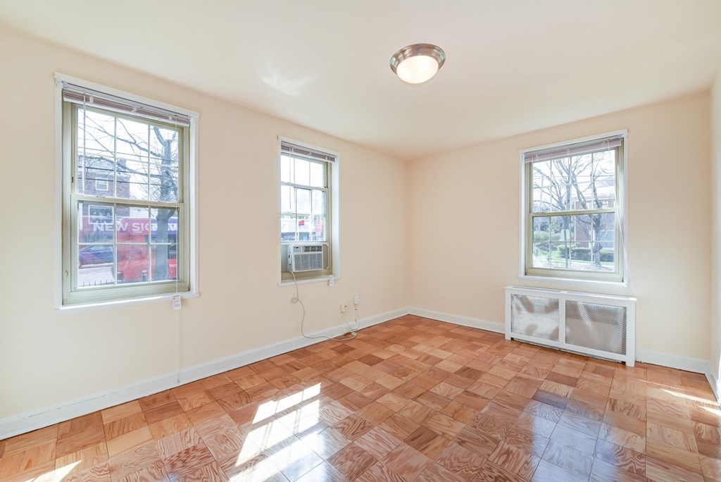 vacant living area with hardwood flooring and large windows at 1401 Sheridan apartments in washington dc