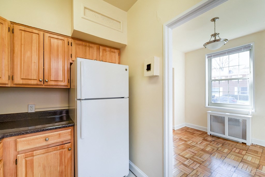 kitchen with wood cabinetry, refrigerator, tile flooring and view of dining area  at 1401 sheridan apartments in washington dc