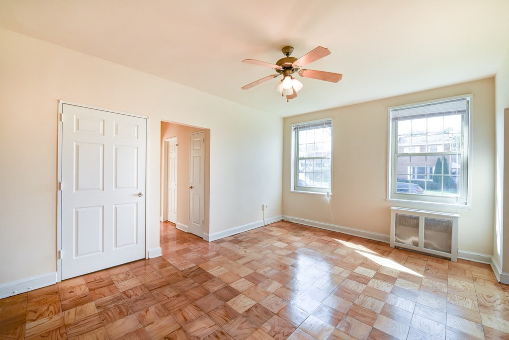 vacant living area with hardwood flooring, ceiling fan, and large windows  at 1401 sheridan apartments in washington dc