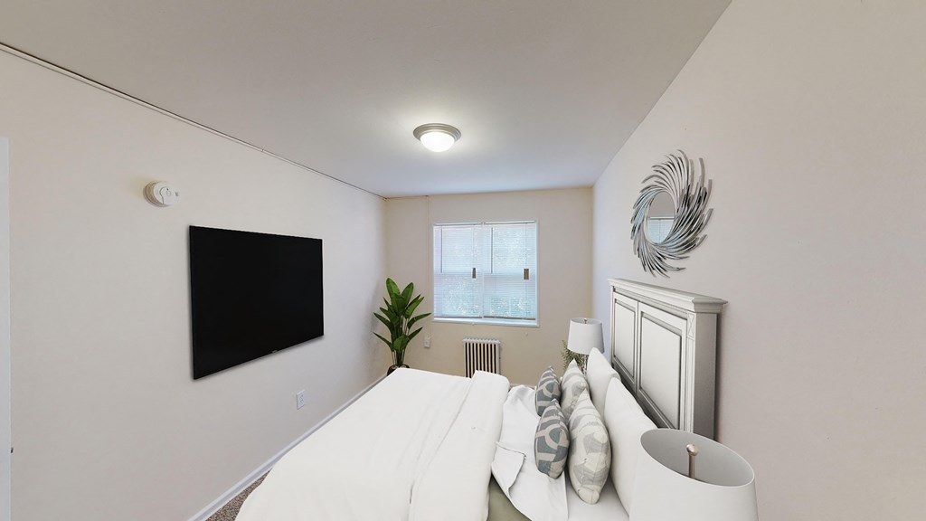 bedroom with bed, nightstand, tv and windows at manor village  tax credit apartments in washington dc
